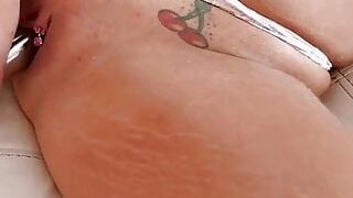 Aroused blonde MILF with big, firm tits and pierced nipples is masturbating on the couch